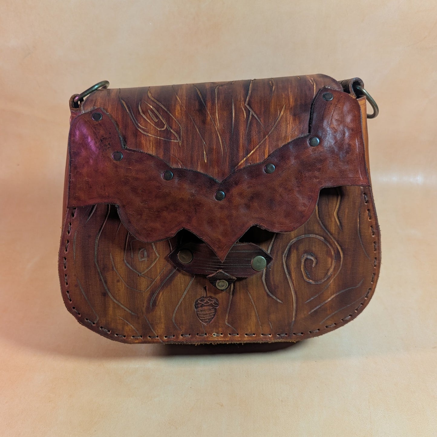 Escarcelle en cuir tanné végétal, façonnée en forme d’écorce d’arbre, avec fermoir en bois de cerf et finitions en laiton vieilli.