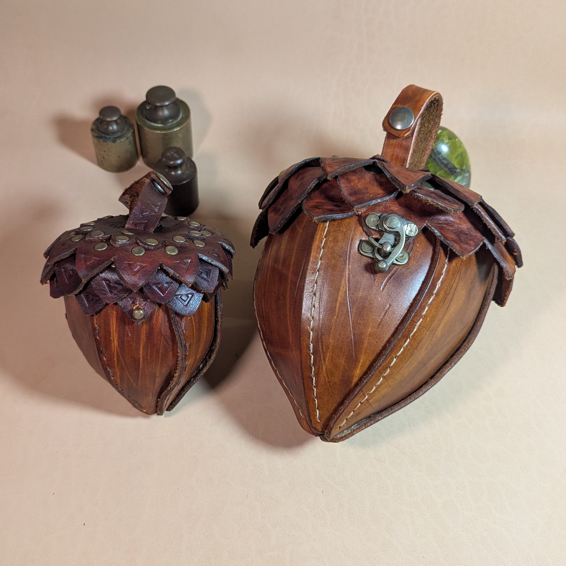 Sacoche en cuir tanné végétal, façonnée en forme de gland, avec rabat à écailles et fermoir en laiton vieilli.