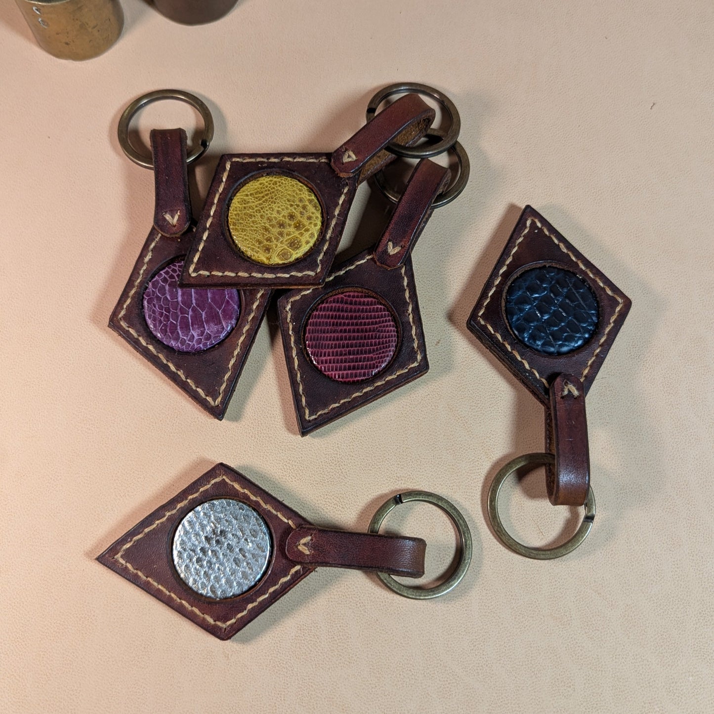 Bijou de sac ou porte-clef en cuir tanné végétal, avec médaillon en cuir exotique (crapaud, serpent, lézard, coq ou alligator), fermoir en laiton vieilli et fil de lin.