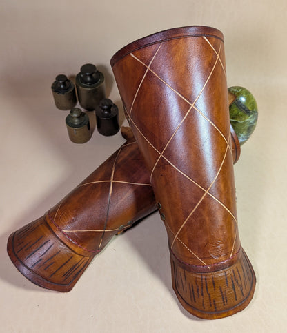 Protèges avant-bras en cuir de bovin tanné végétal, avec boucle en laiton vieilli et sangles en cuir pour un ajustement personnalisé.