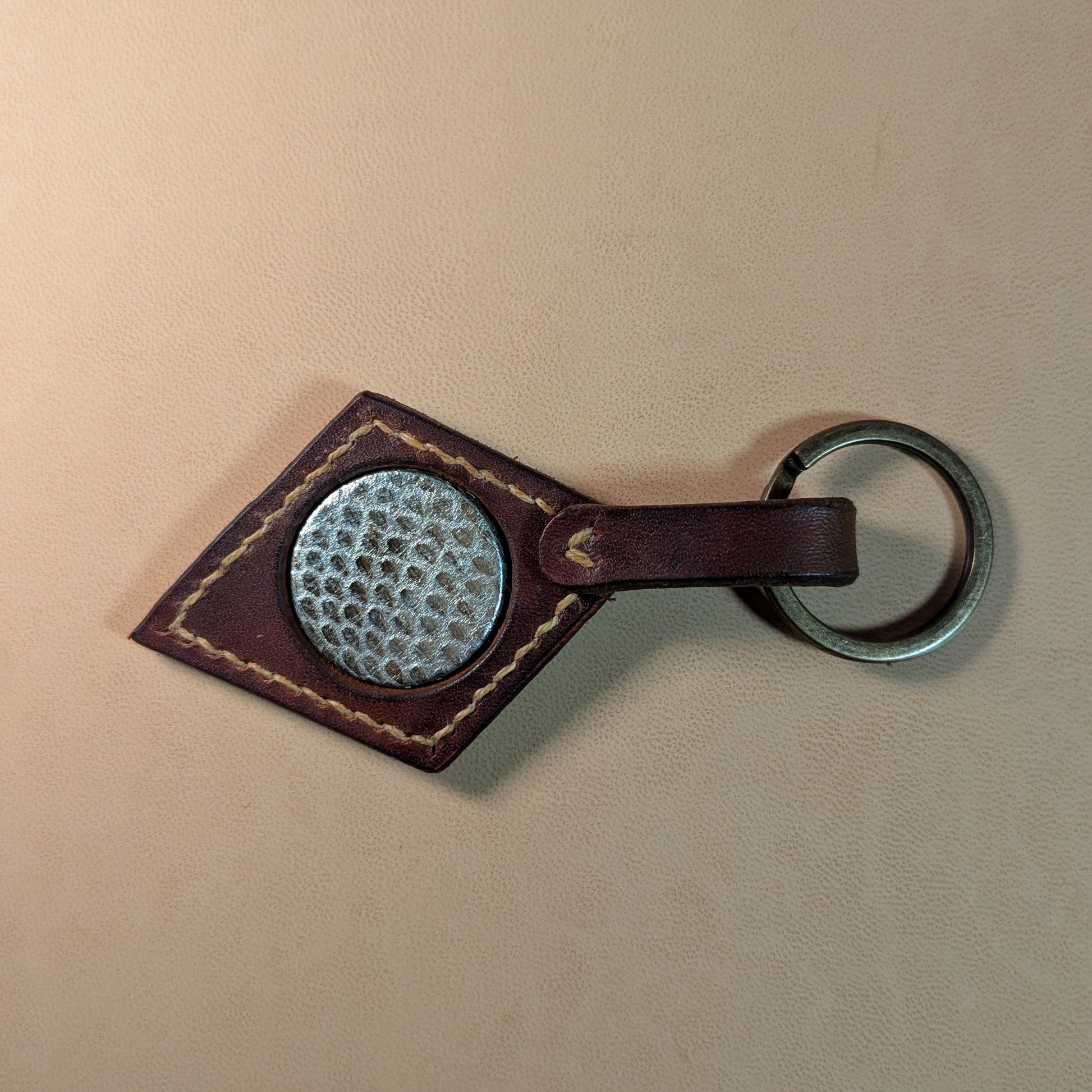 Bijou de sac ou porte-clef en cuir tanné végétal, avec médaillon en cuir exotique (crapaud, serpent, lézard, coq ou alligator), fermoir en laiton vieilli et fil de lin.