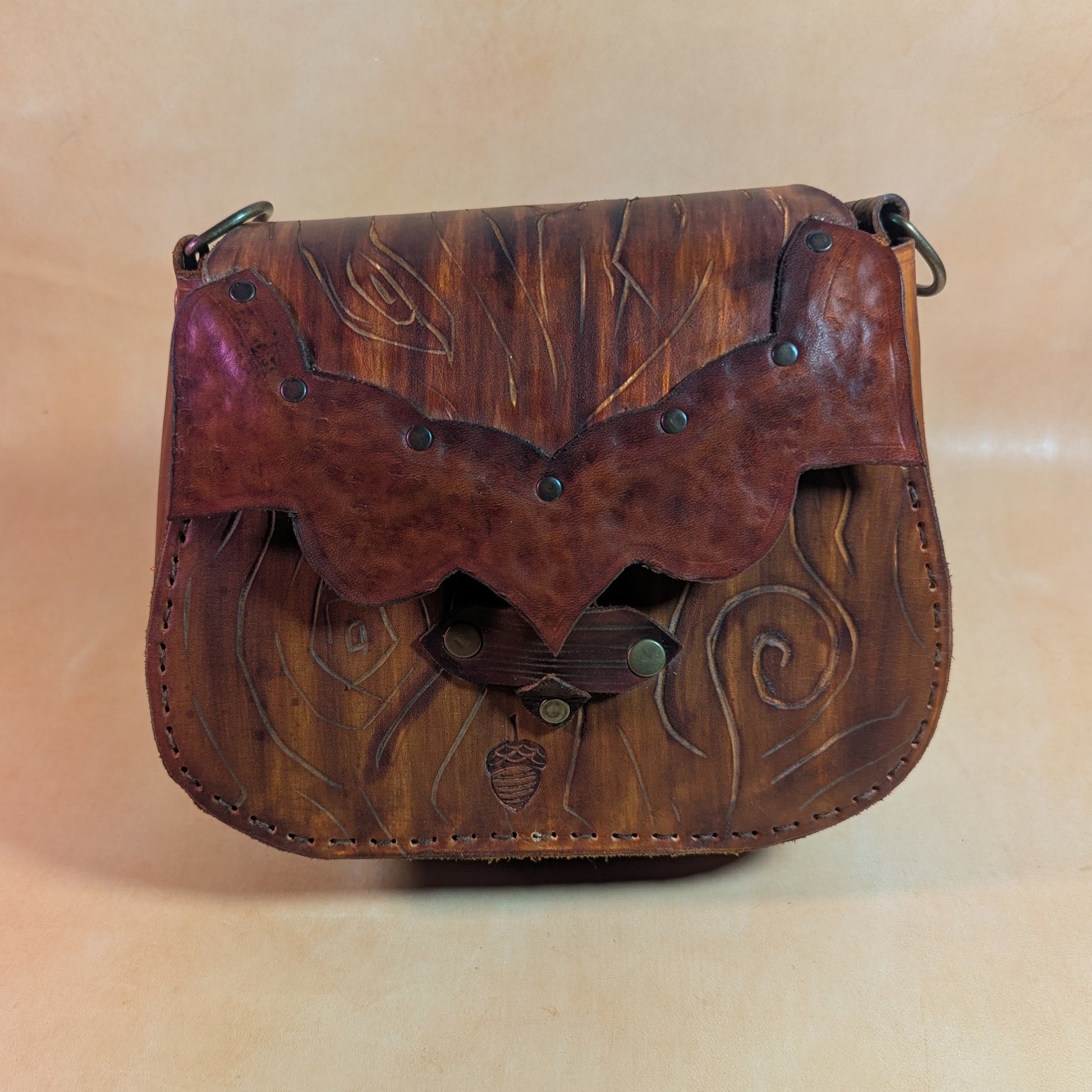 Escarcelle en cuir tanné végétal, façonnée en forme d’écorce d’arbre, avec fermoir en bois de cerf et finitions en laiton vieilli.
