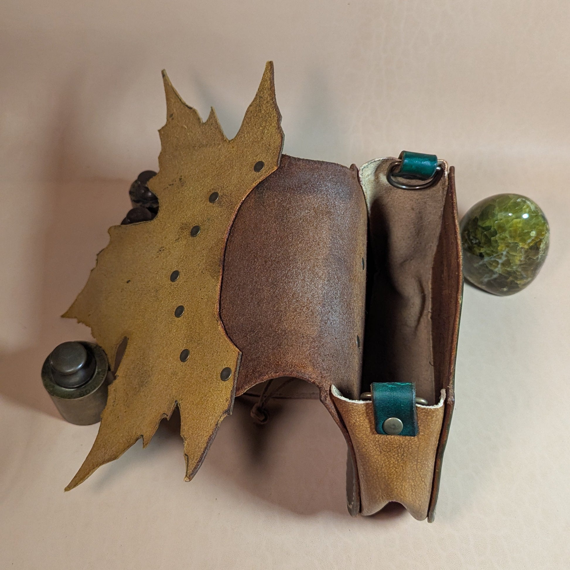 Escarcelle en cuir tanné végétal, façonnée en forme de feuille de platane, avec fermoir en bois de cerf et finitions en laiton vieilli.