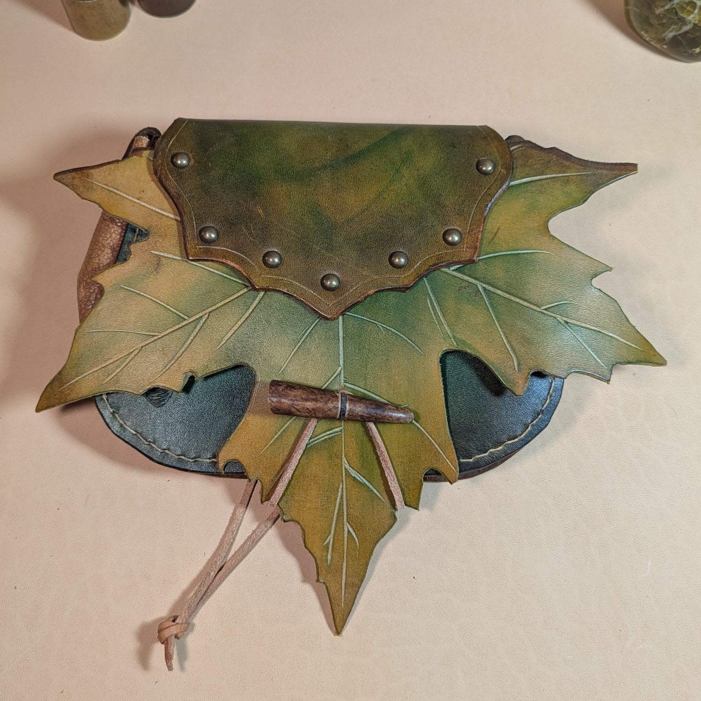 Escarcelle en cuir tanné végétal, façonnée en forme de feuille de platane, avec fermoir en bois de cerf et finitions en laiton vieilli.