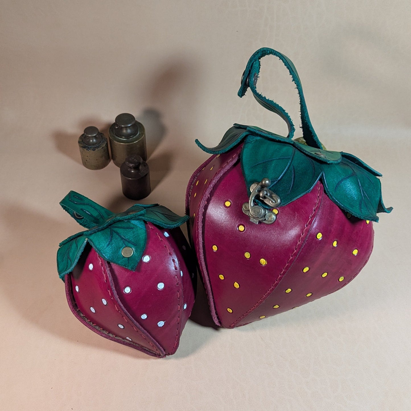 Sacoche en cuir tanné végétal, façonnée à la main en forme de fraise, avec feuilles cousues à la main et fermoir en laiton vieilli.