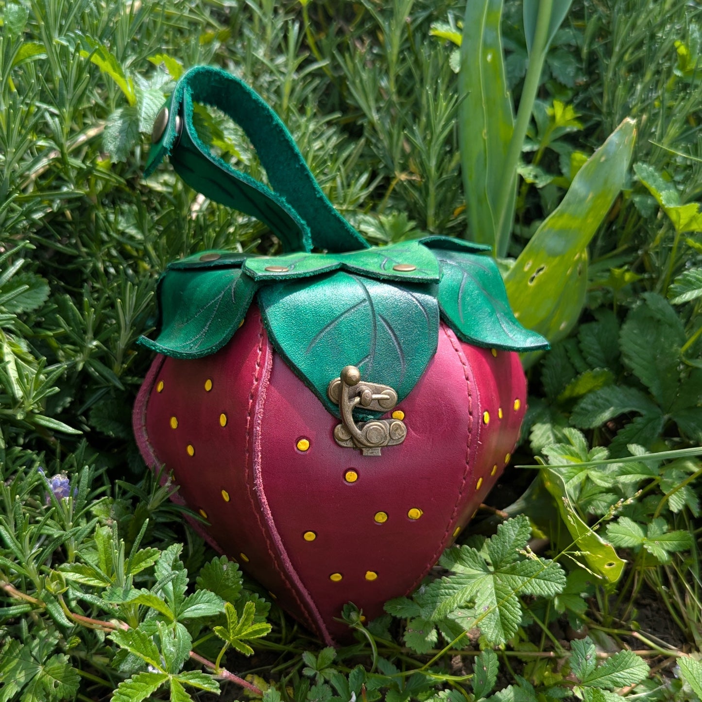 Sacoche en cuir tanné végétal, façonnée à la main en forme de fraise, avec feuilles cousues à la main et fermoir en laiton vieilli.