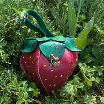 Sacoche en cuir tanné végétal, façonnée à la main en forme de fraise, avec feuilles cousues à la main et fermoir en laiton vieilli.
